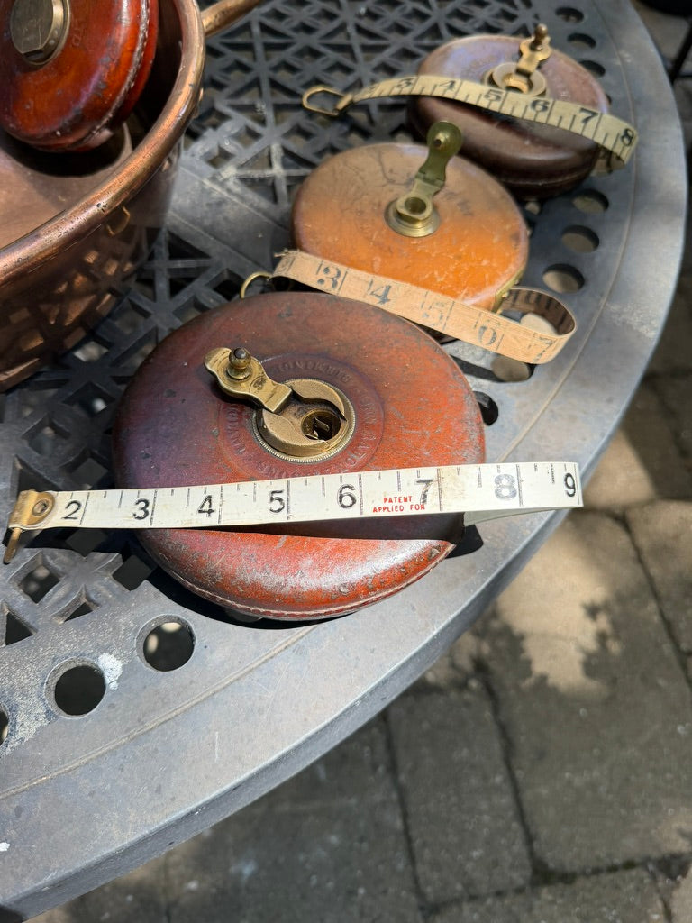 A vintage English leather tape measure with brass hardware and original woven tape, beautifully worn from decades of use. An ideal addition to a sewing room, library, workshop, or cabinet of curiosities.