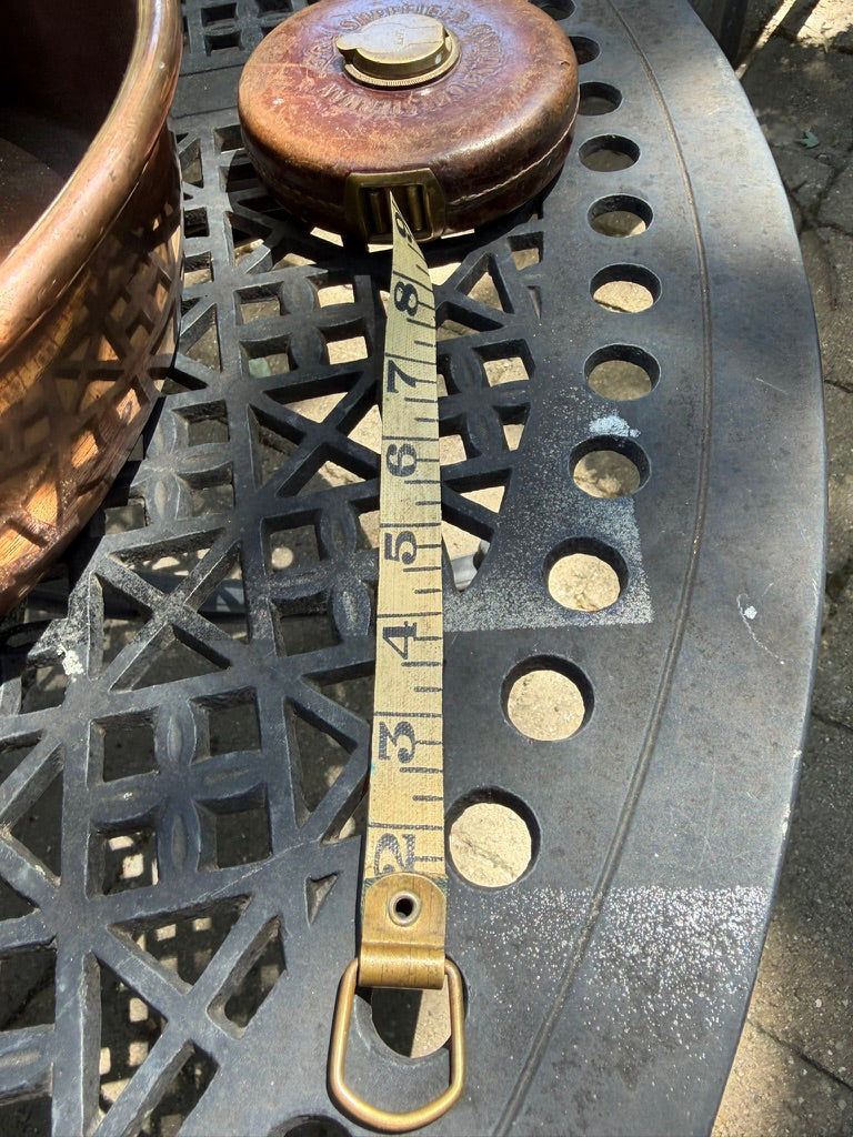 A vintage leather tape measure featuring brass hardware, woven cloth tape, and beautiful aged patina. A charming collectible for sewing rooms, libraries, and heritage-inspired interiors.