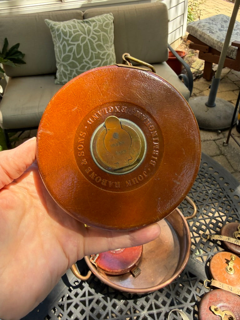 A beautifully crafted antique 66-foot leather measuring tape by John Rabone & Sons of Birmingham, England. Encased in richly aged leather with solid brass fittings and its original woven tape, this piece reflects the exceptional craftsmanship for which Rabone became renowned.