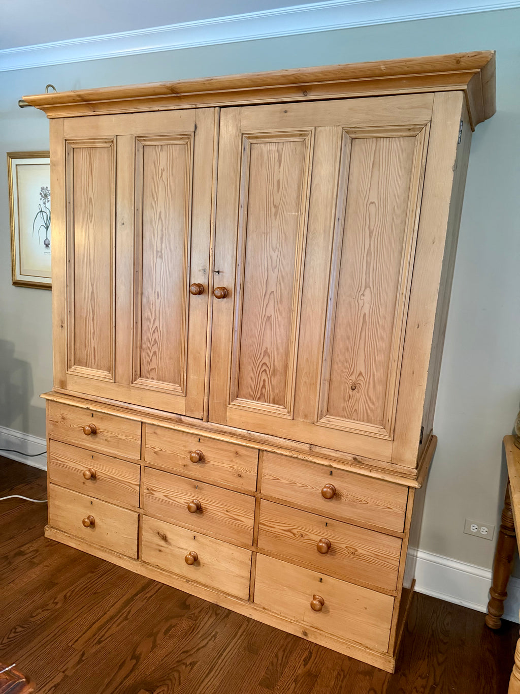 An authentic English Victorian pine Housemaid's Cupboard featuring two interior shelves, nine hand-dovetailed drawers, original pine knobs, and its original working key. A timeless antique linen press sourced from England.