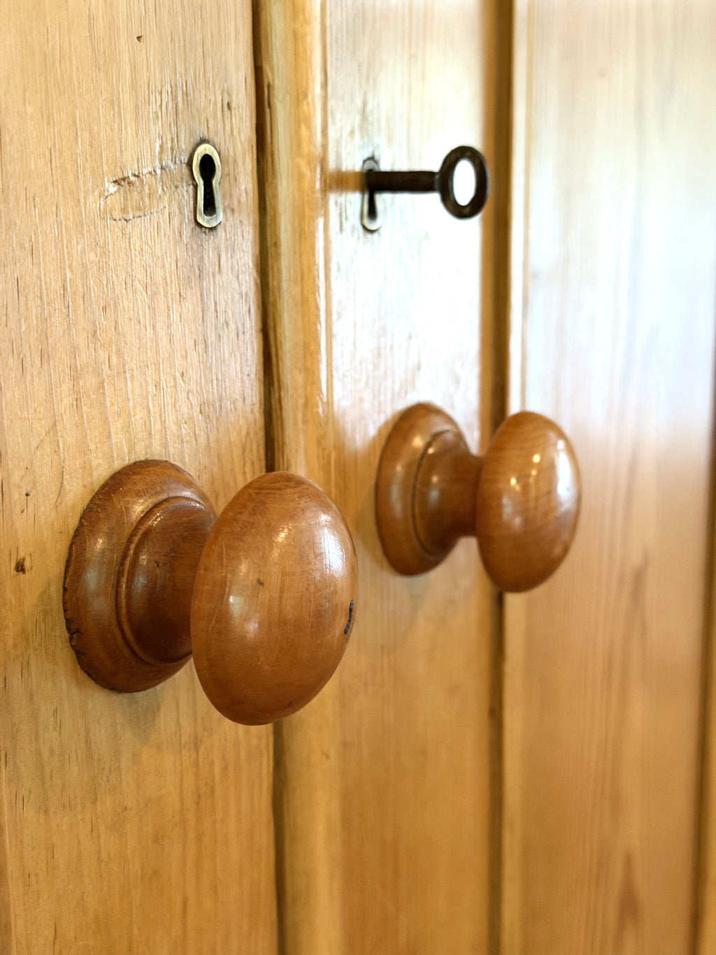 An authentic English Victorian pine Housemaid's Cupboard featuring two interior shelves, nine hand-dovetailed drawers, original pine knobs, and its original working key. A timeless antique linen press sourced from England.