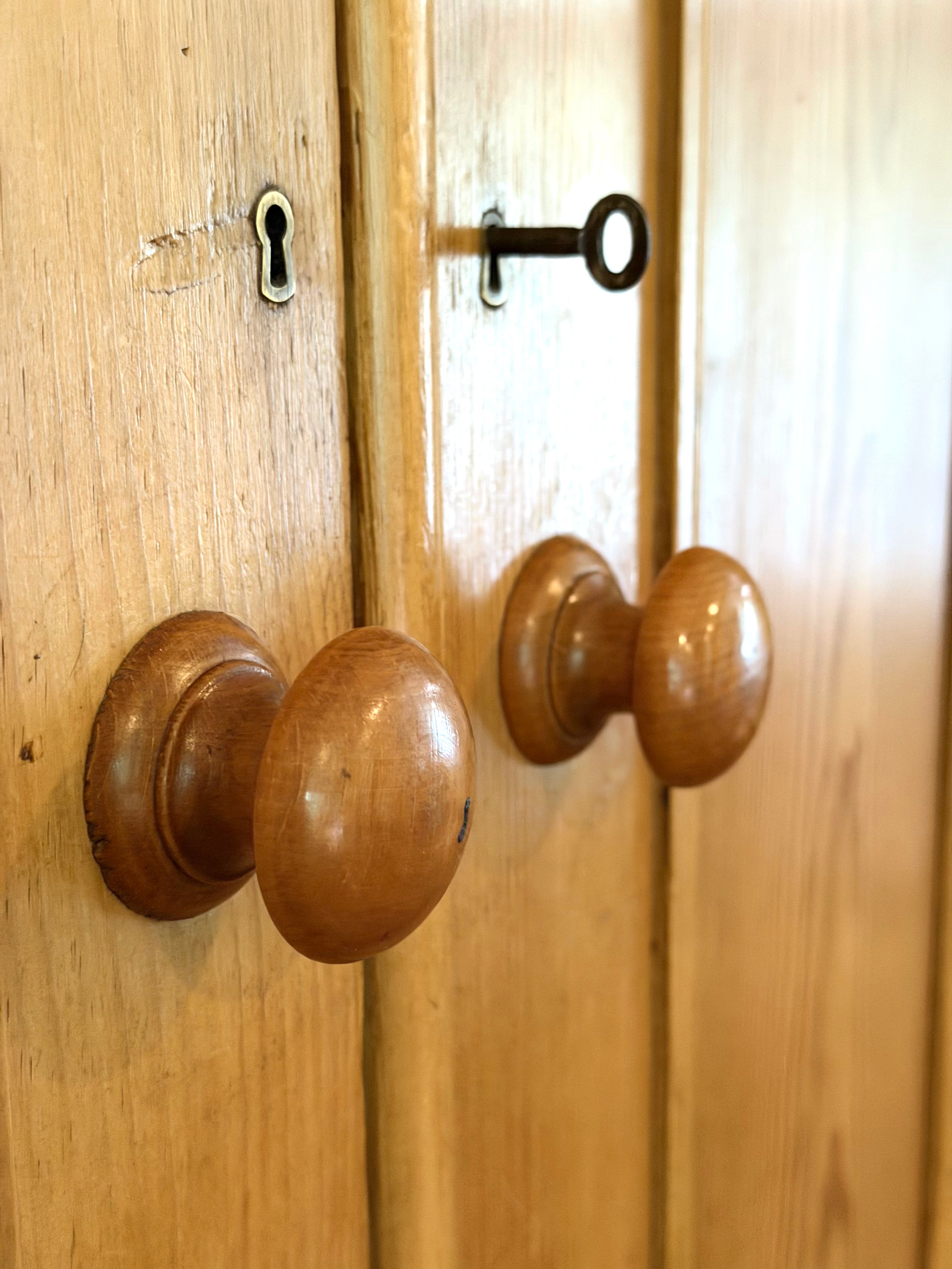 An authentic English Victorian pine Housemaid's Cupboard featuring two interior shelves, nine hand-dovetailed drawers, original pine knobs, and its original working key. A timeless antique linen press sourced from England.