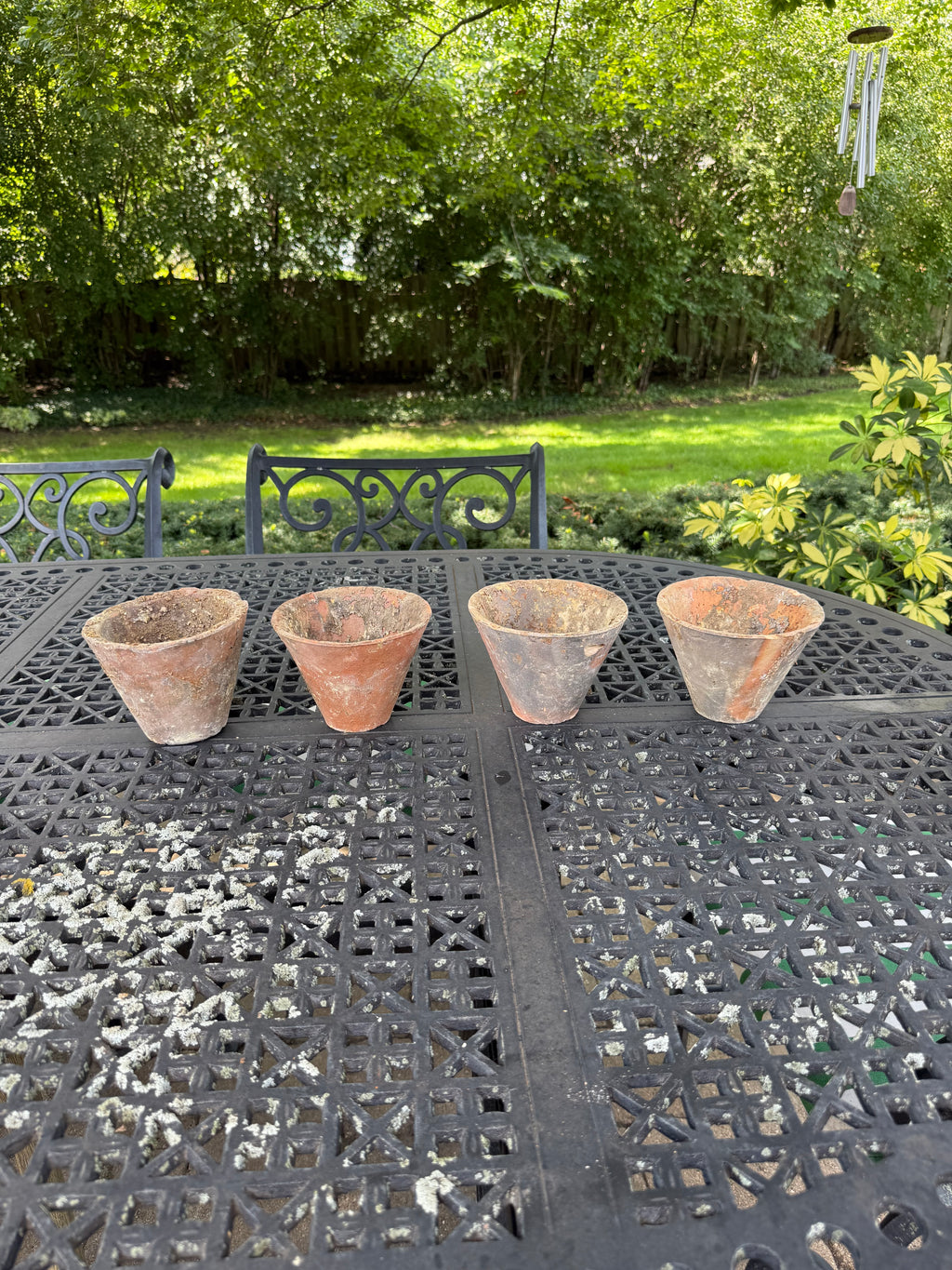Four antique tapered terracotta pots arranged in a row outdoors
