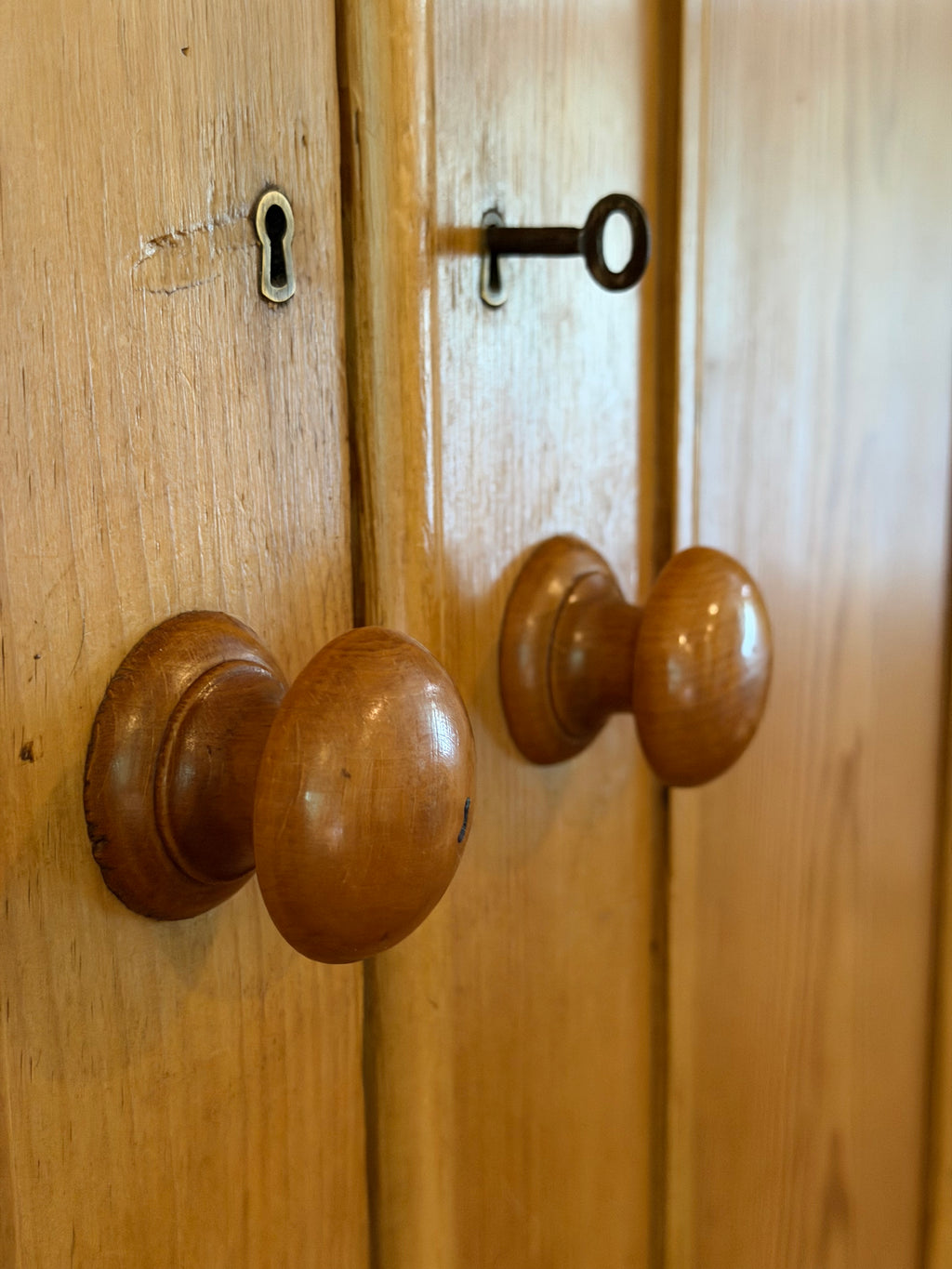 An authentic English Victorian pine Housemaid's Cupboard featuring two interior shelves, nine hand-dovetailed drawers, original pine knobs, and its original working key. A timeless antique linen press sourced from England.