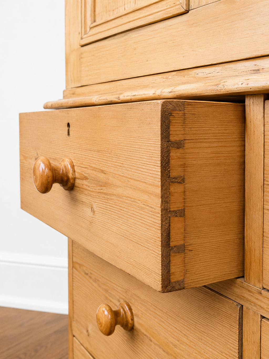 An authentic English Victorian pine Housemaid's Cupboard featuring two interior shelves, nine hand-dovetailed drawers, original pine knobs, and its original working key. A timeless antique linen press sourced from England.