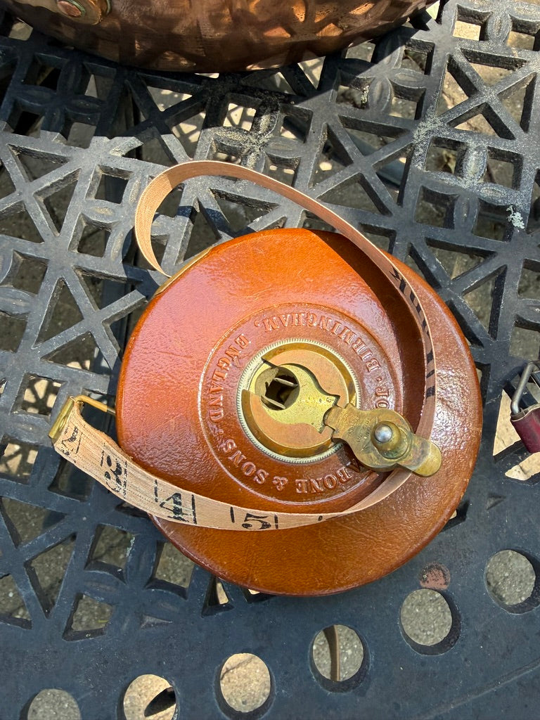 A vintage leather measuring tape with  tan leather and brass hardware