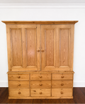 An authentic English Victorian pine Housemaid's Cupboard featuring two interior shelves, nine hand-dovetailed drawers, original pine knobs, and its original working key. A timeless antique linen press sourced from England.