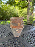 Stack of four antique English terracotta pine resin pots on outdoor table
