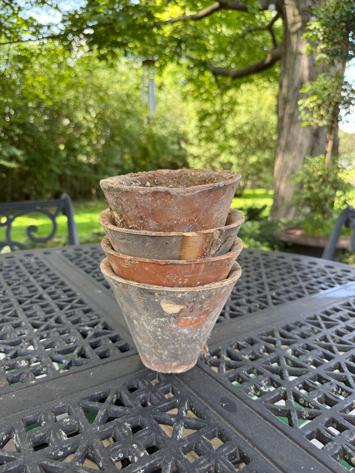 Stack of four antique English terracotta pine resin pots on outdoor table